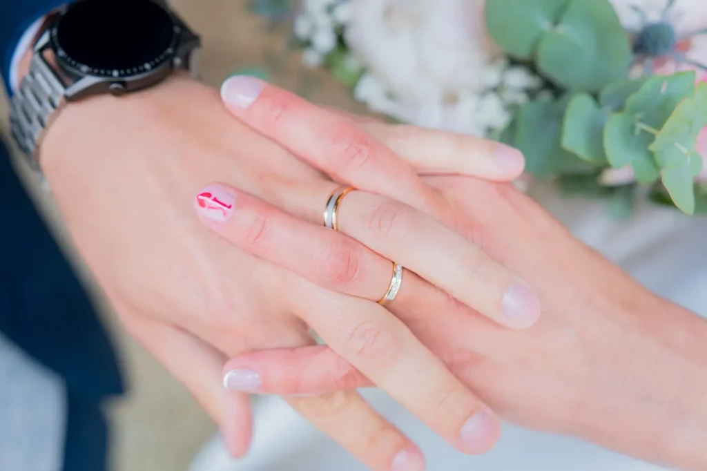 Les deux jeunes mariés, main dans la main montrant leurs alliances.